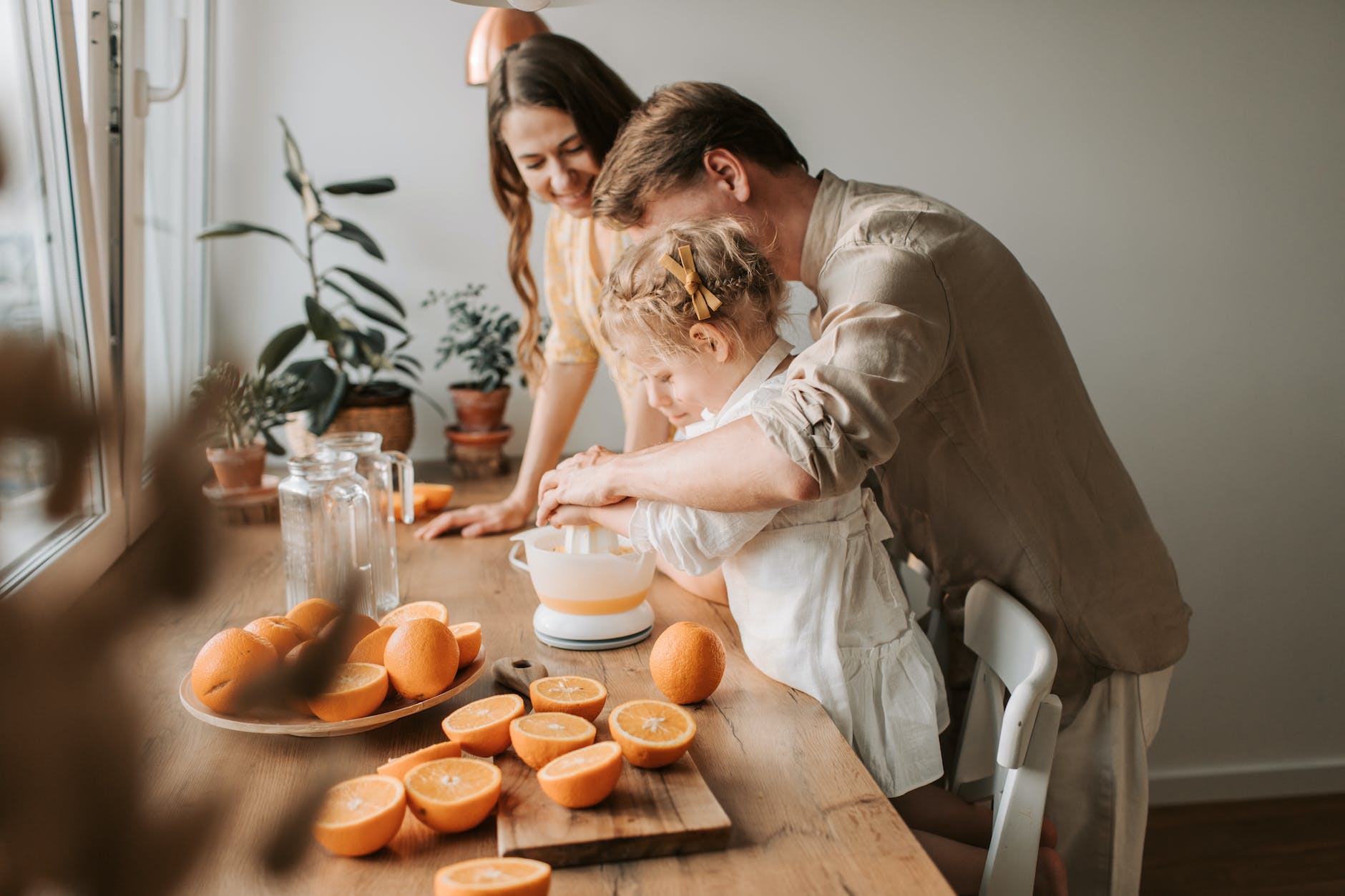 a man and daughter extracting juice from orange fruit